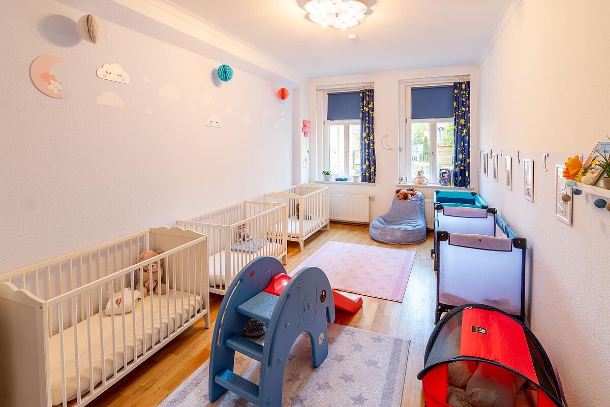 Blick in einen hellen Raum mit mehreren Kinderbetten