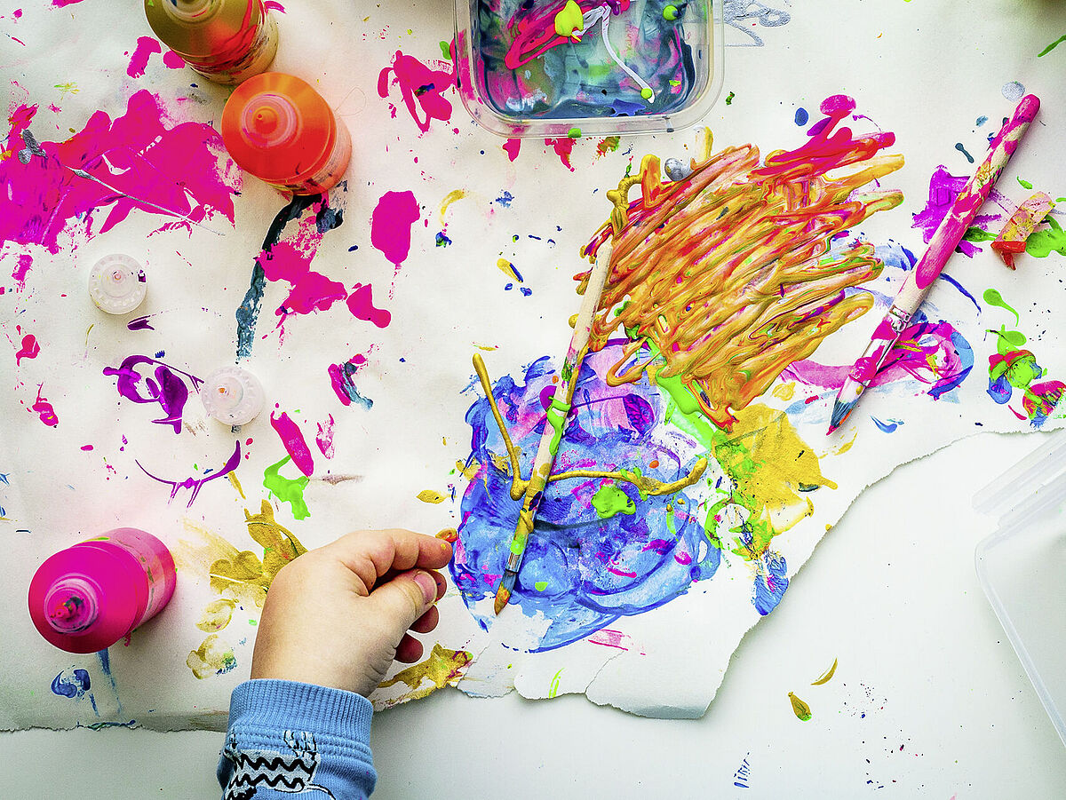 Kinderhand beim malen mit bunten Farben
