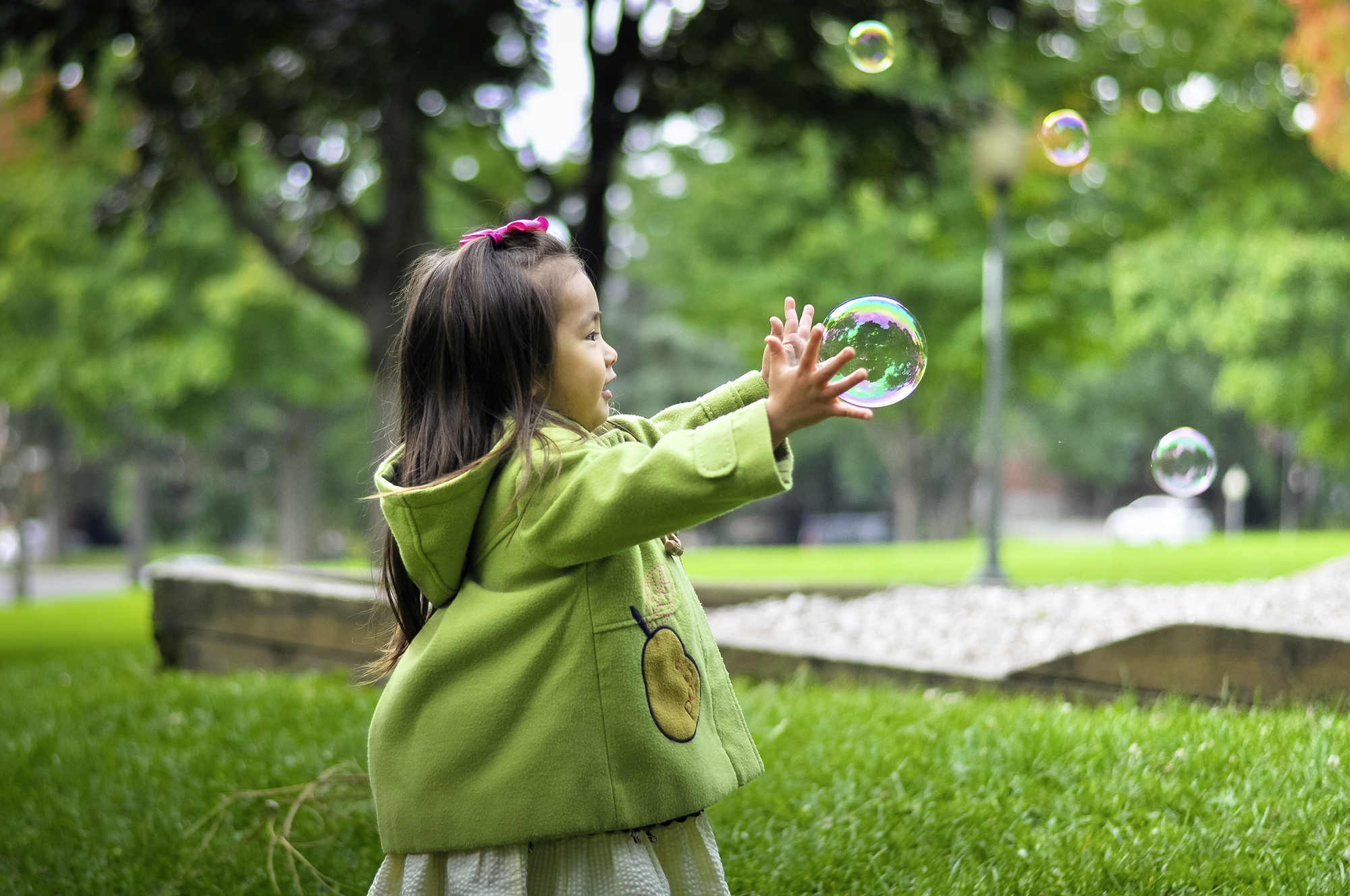 Kind auf Wiese spielt mit Seifenblase