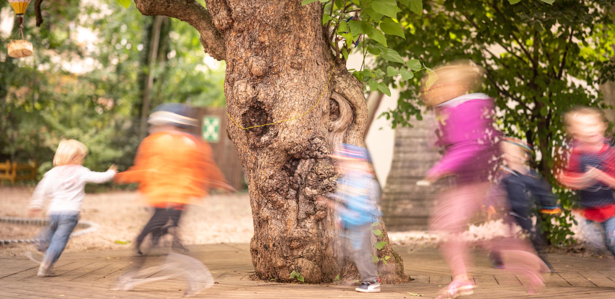 Kinder rennen um einen Baum